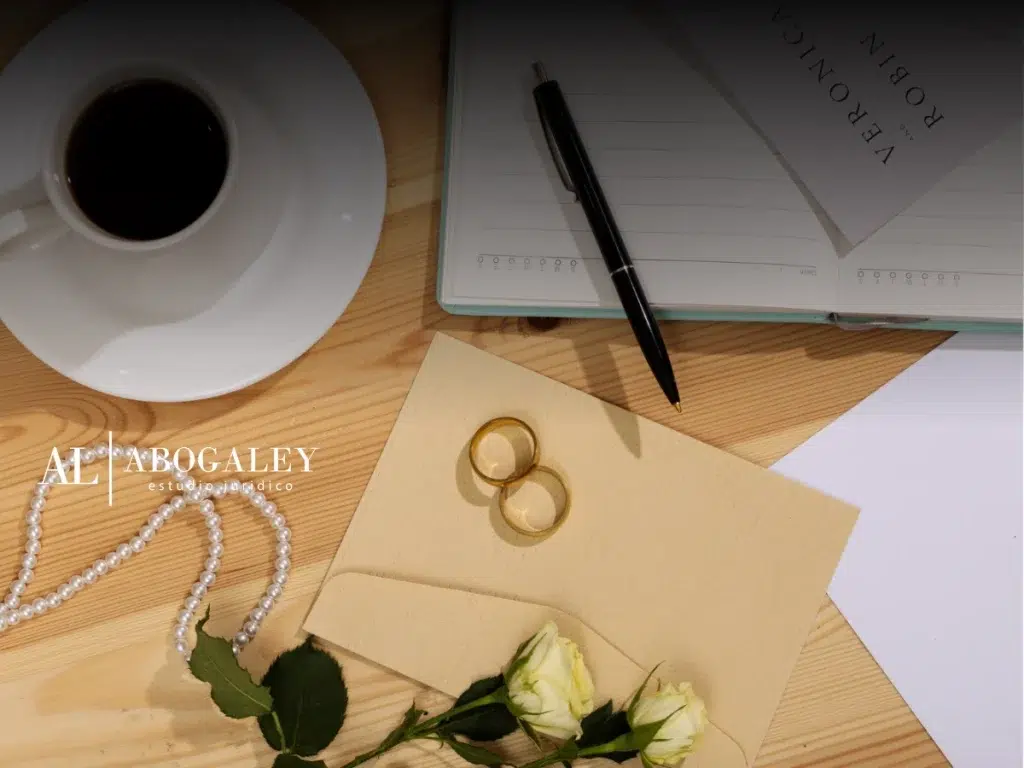 Escritorio donde se muestra encima un sobre, unas flores amarillas, unas argollas, una libreta, lápiz y taza de cafe. Nueva ley de matrimonio civil en Chile: ¿Qué necesitas saber?