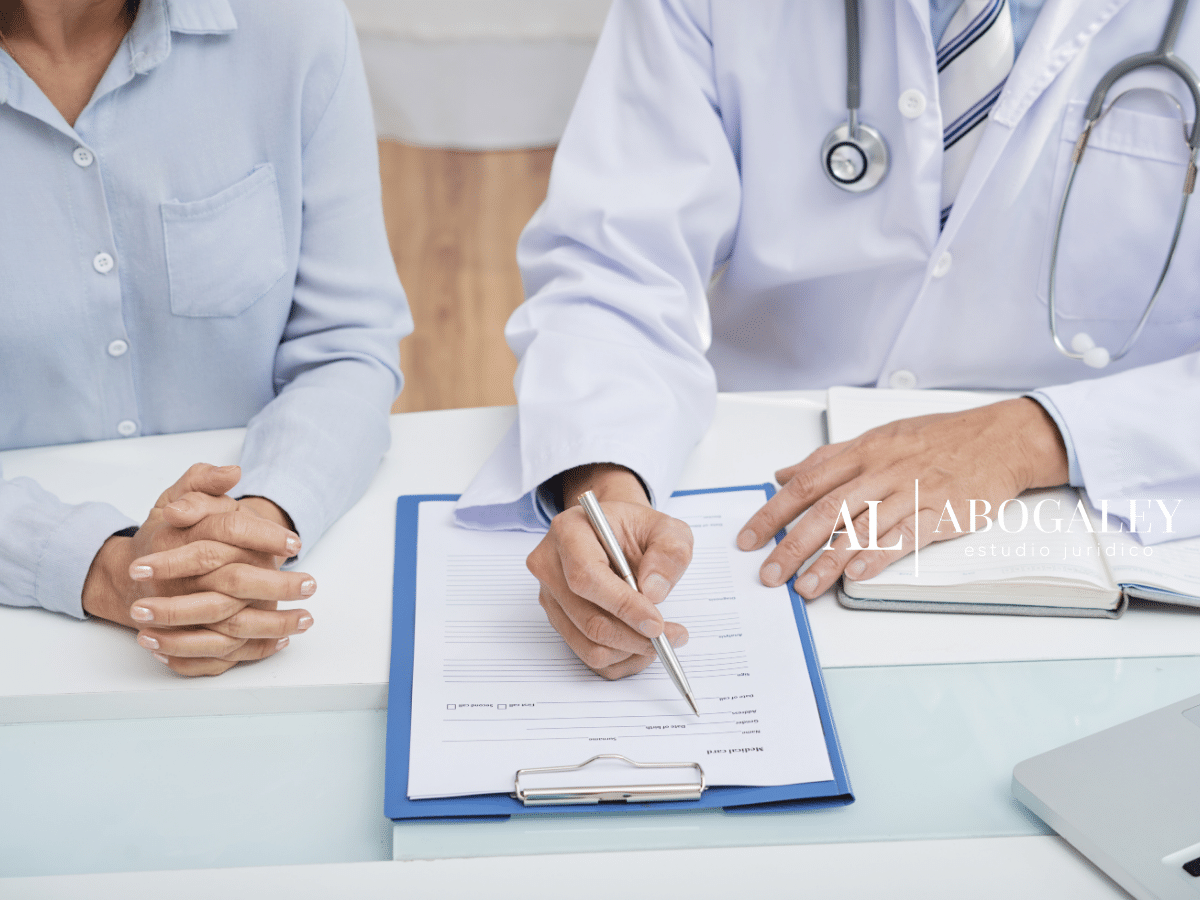 Médico con paciente sentados en un escritorio discutiendo el Autodespido con licencia médica.